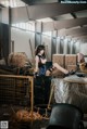 A woman sitting on top of a barrel in a warehouse.