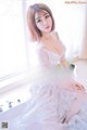 A woman in a white dress sitting on a bathtub.