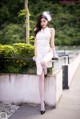 A woman in a white dress sitting on a ledge.